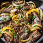 Tender beef liver cooked in a cast-iron skillet with caramelized onions and fresh parsley, perfect for a classic carnivore diet meal.